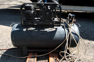 Old used compressor, used and very worn out compressor standing in open area at construction site.