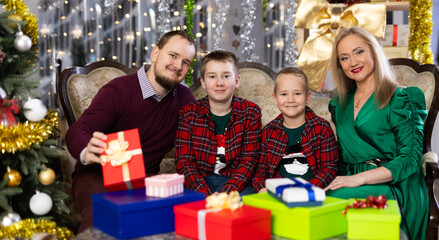 Portrait of happy family with two children celebrating Christmas next to Christmas tree