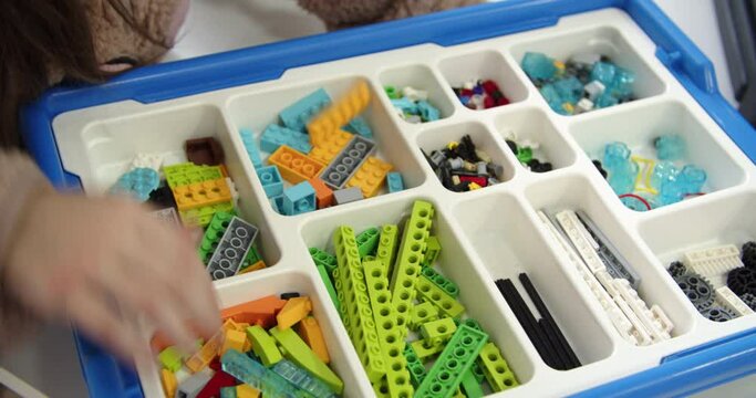 A child plays with a Lego constructor. Close-up of a girl's hands assembling a lego