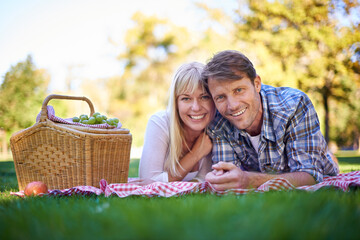 Happy couple, portrait and smile at park picnic or fruit basket for holiday snack for relationship,...