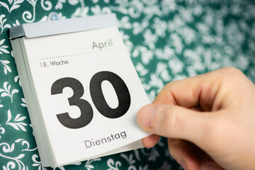 Hand reisst 30. April Zettel vom Kalender