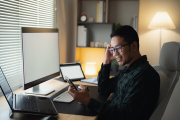Smiling Asian Man developer programmer with Smartphone at Home Office. Happy Asian man using...