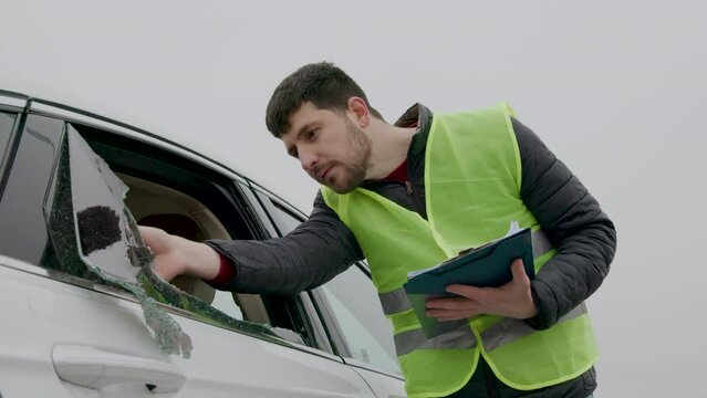 Insurance inspector documenting a car with a broken window - a vivid portrayal of vandalism accurately captured