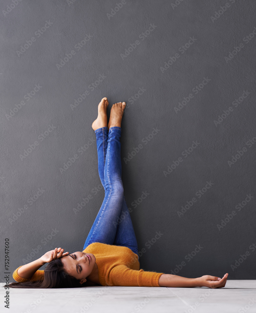 Sticker Woman, style and wall background for laying, feet and relaxing on floor in sleep with fashion. Female person, positive and chill at home for happiness, casual and wellness in jeans with toes in air