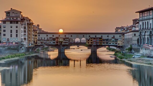Sunset view of Florence Ponte Vecchio over Arno River in Florence timelapse, Italy. Florence architecture. One of the main landmarks in Florence with orange sky above