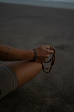 Chica realizando poses de yoga y mudras en la playa al atardecer en tonos marrones