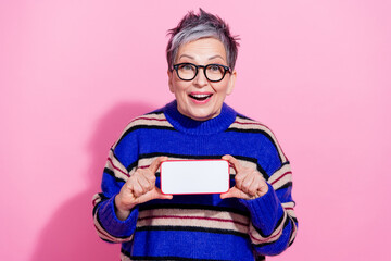 Photo of attractive pensioner woman device horizontal white screen dressed stylish blue striped clothes isolated on pink color background
