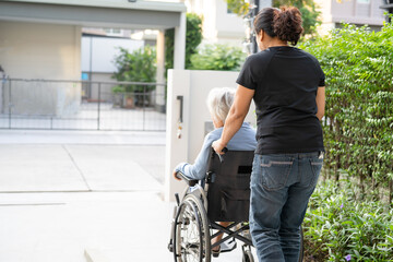 Caregiver help and care Asian elderly woman patient sitting on wheelchair to ramp in nursing...