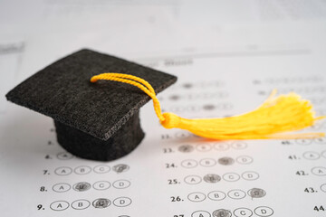 Graduation gap hat and pencil on answer sheet background, Education study testing learning teach...
