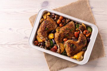 Chicken legs baked in a roasting pan with vegetables.