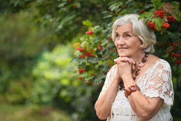 Portrait of happy senior woman posing at forest