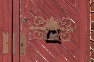 Red door with a large metal door handle with decorations.