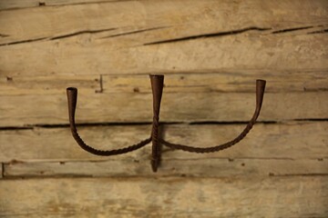 Old metal candle holder hanging on log wall.
