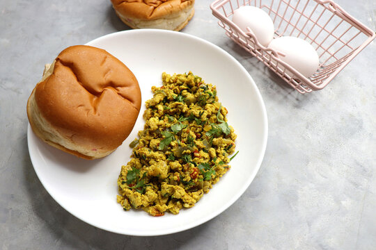 Anda Masala Bhurji or Spicy Indian scrambled eggs with bread or Bun Pav, a popular street food in Mumbai. Served in a white plate along with copy space. egg bhurji or parasi akuri. with jowar bhakri.