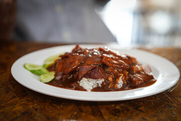 Close up and selective focus crispy pork in sauce with rice on table at restaurant, Thailand food