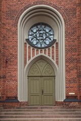 Obraz premium A wooden door with arch and round window on a red brick old building.