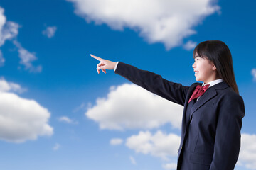 青空の下で指差しをする女子学生