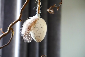 Przystrojone białe jajko na Boże Narodzenie. Ozdoba świąteczna w postaci jajka przyozdobionego małym piórem od perliczki.  - obrazy, fototapety, plakaty