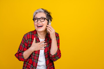 Portrait of funky positive aged lady communicate telephone laugh empty space isolated on yellow...