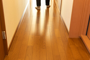 木の廊下を歩いて行く人物の足