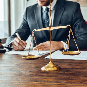 Notary signing document at wooden table in office, focus on scales