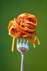 Fork full of spaghetti and red sauce, pure green background