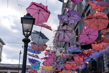 A street with many colorful umbrellas hanging from a lamp post