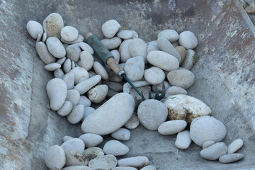 Piedras de río  con herramienta de jardinería  dentro de una carretilla de obra