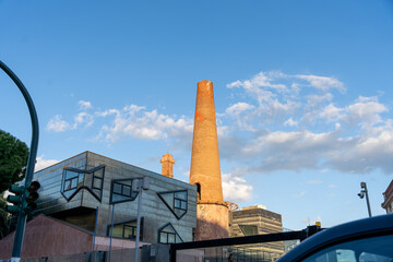 A brick building with a tall chimney and a car in the background
