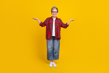 Full size portrait of cheerful aged lady arms palms hold demonstrate empty space vs scales isolated on yellow color background