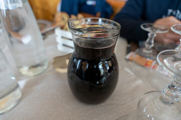 A pitcher of dark liquid sits on a table with a few other items