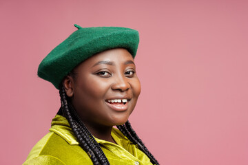 Smiling, happy African American woman with stylish braids hair wearing green beret and casual outfit