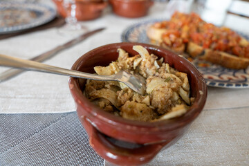A bowl of food with a fork in it sits on a table