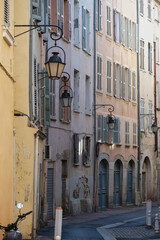 Fototapeta na wymiar Romantic backstreet road alley in historic old town downtown Toulon, France with Mediterranean style house building facades and old little piazzas fountains picturesque city scenery 