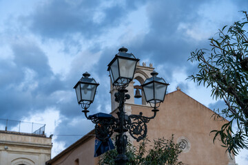 Three street lamps are lit up in the evening