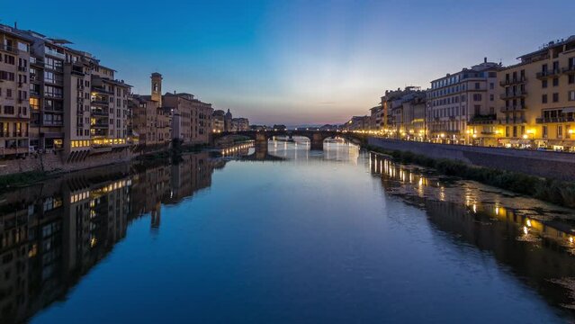 Twilight scene of Ponte Santa Trinita (Holy Trinity Bridge) day to night transition panoramic timelapse over River Arno with reflections on water after sunset, old houses on the side. Florence, Italy