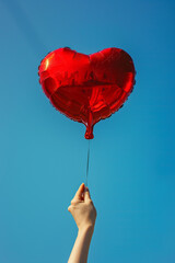 heart shaped balloon in the hands on a blue background