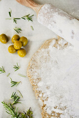 View from above olives and rosemary in the mass on top of rustic wood.