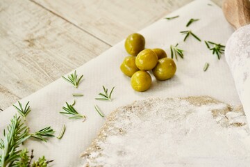 View from above olives and rosemary in the mass on top of rustic wood.