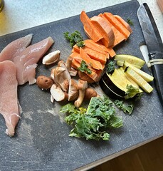 board with chopped vegetables, sweet potato sticks, eggplant, shitake mushrooms, kale, chicken pieces, preparing dinner