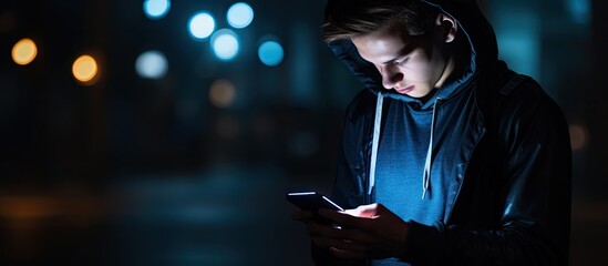 Contemplative young man in a hoodie using mobile phone in urban setting - Powered by Adobe