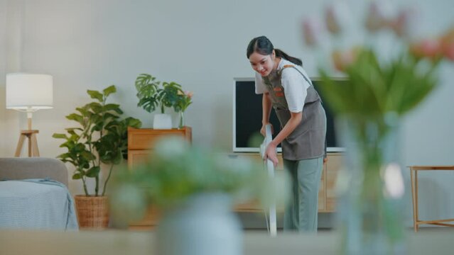 Female housekeeper is cleaning mop the floor and vacuum dust on floor by vacuum cleaner in living room and bedroom.