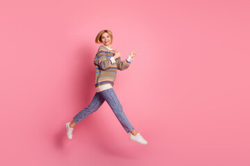 Full size photo of nice woman wear ornament pullover jumping indicating at discount run empty space isolated on pink color background