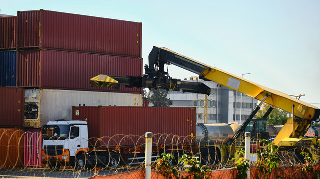 Unloading of cargo container. Reach-stacker is ready to pick container up from truck. Cargo logistics terminal