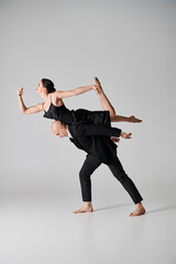barefoot young woman in black dress balancing gracefully during dance performance with man