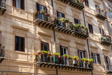 A row of apartments with balconies and potted plants - obrazy, fototapety, plakaty