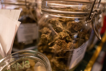 A jar of marijuana is sitting on a table next to a jar of something else