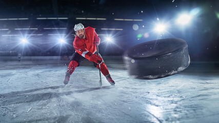 Ice hockey rink arena with professional player shooting the puck with hockey stick. Focus on 3D...