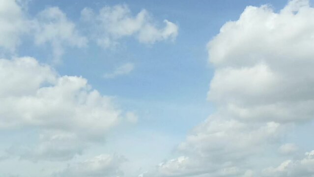 Bright white clouds fly across the bright blue sky. The sky is clear in the afternoon. Background view of clouds moving in the wind. Copy space