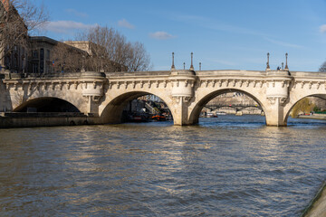 A bridge spans a river with boats on it - obrazy, fototapety, plakaty